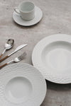 It imparts a contemporary and unique style to the table. It has plates and saucers with textured edges, subtly conical cups and ergonomic handles. 