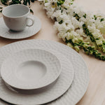 It imparts a contemporary and unique style to the table. It has plates and saucers with textured edges, subtly conical cups and ergonomic handles. 